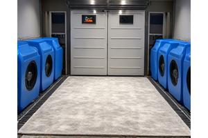 Una alfombra grande se está secando en una sala de secado profesional con potentes ventiladores de aire forzado. La alfombra está estirada y levanta ligeramente para permitir una circulación máxima del aire. Colores vibrantes de la alfombra, transmitiendo tecnología de secado rápido.